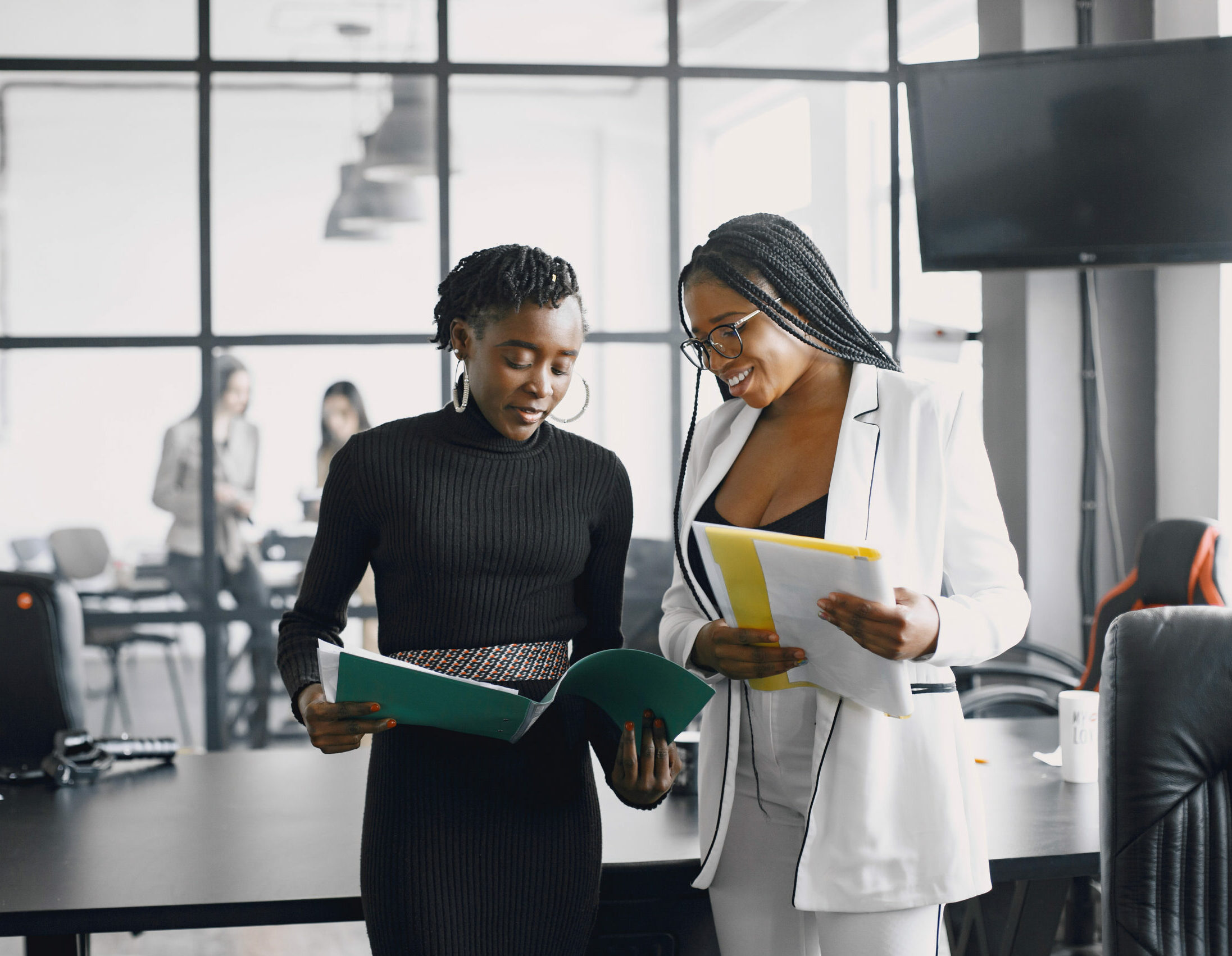 Business women talking near the desk during a coffee break in the hallway of the big corporation